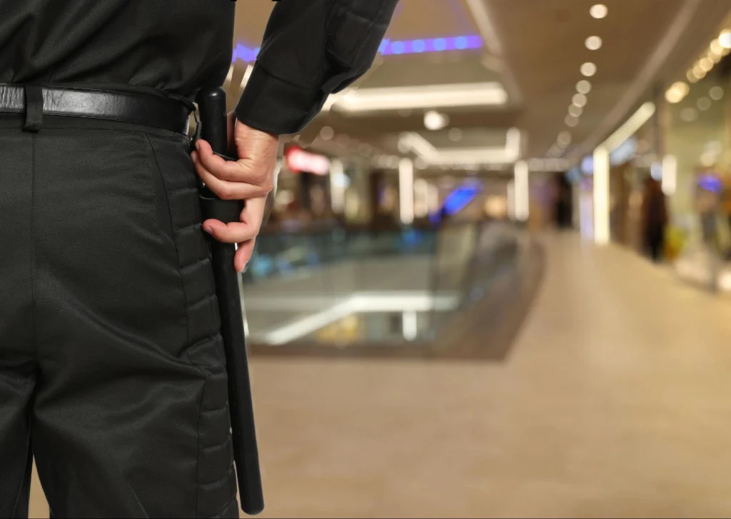 Security guard patrolling a shopping mall while holding a baton.