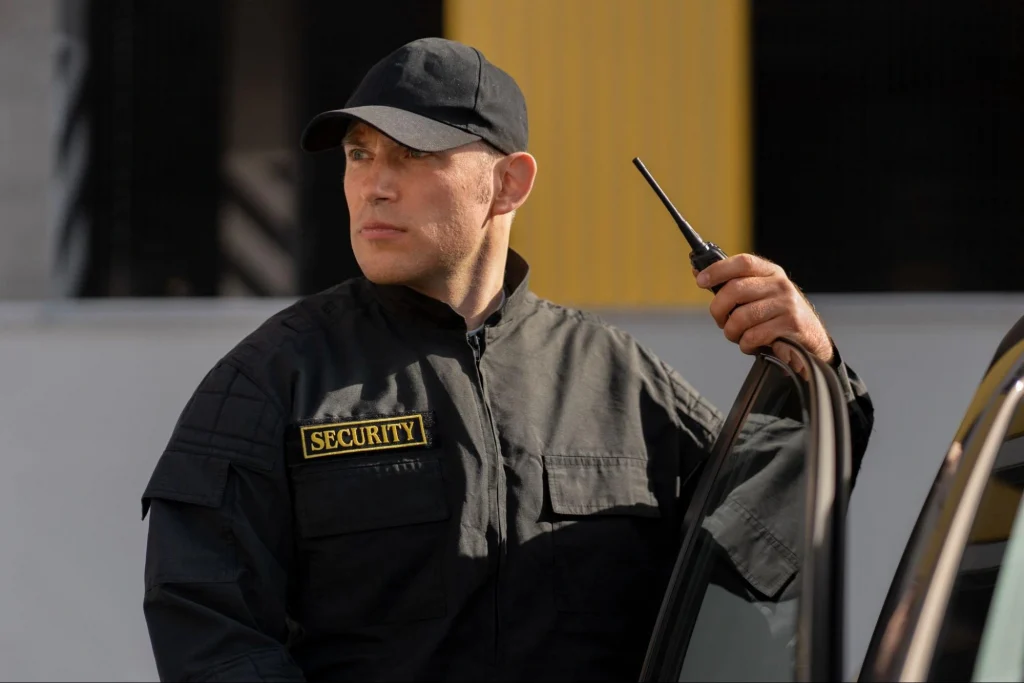 Security guard exiting a vehicle while using a radio for communication.