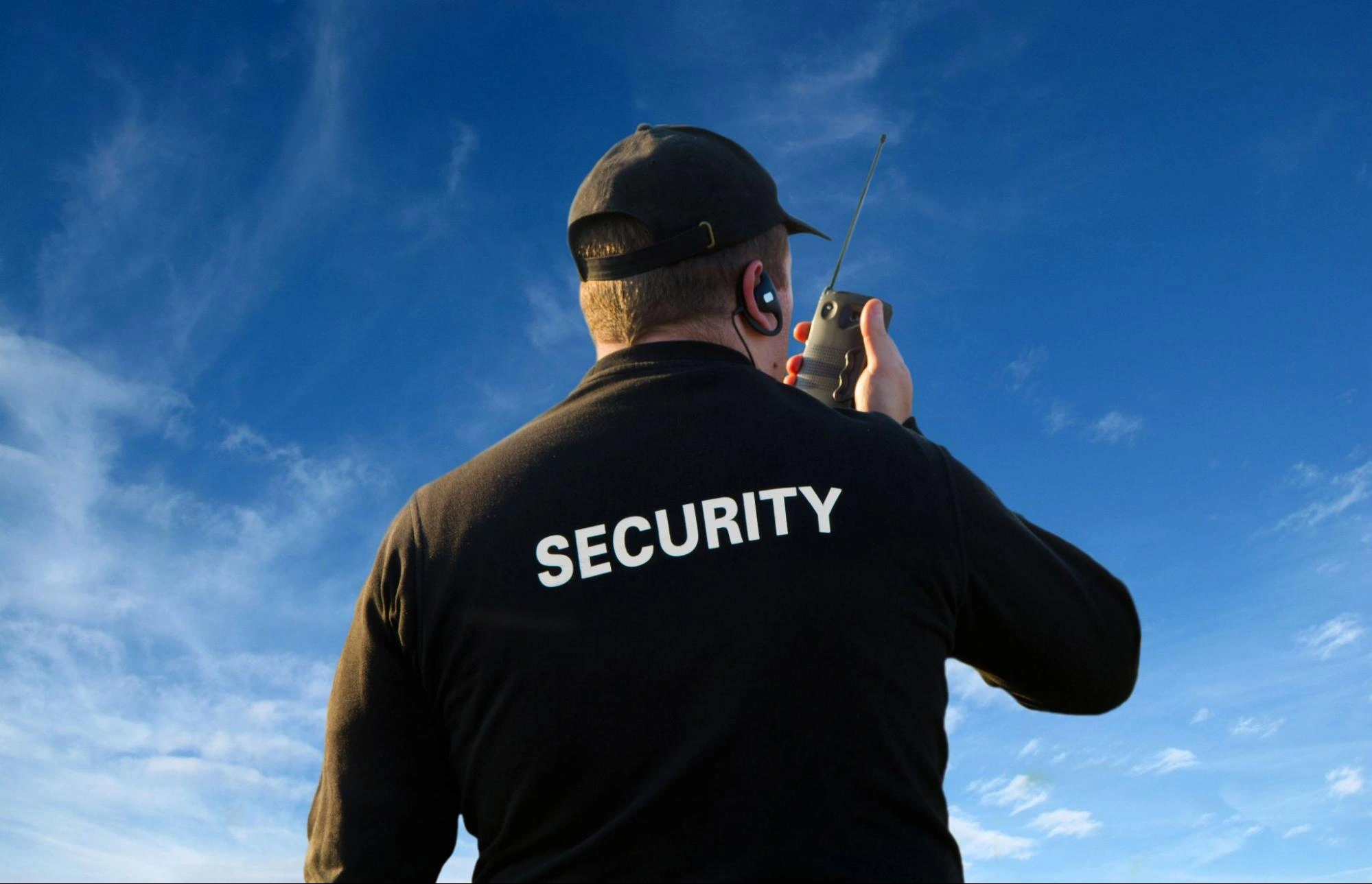 Security guard using a radio for communication while on duty outdoors.