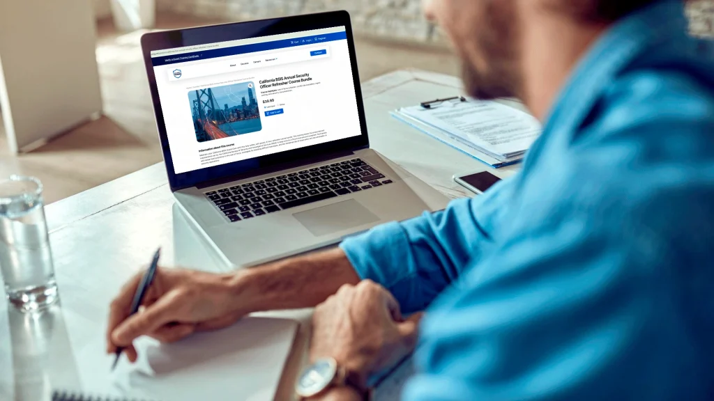 Man taking notes while viewing security guard training classes on the Guard Training online platform.