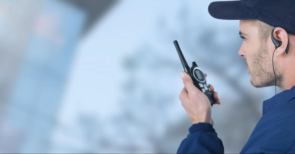 Professional security guard communicating via two-way radio during duty, featured in Guard Training's online guard training video