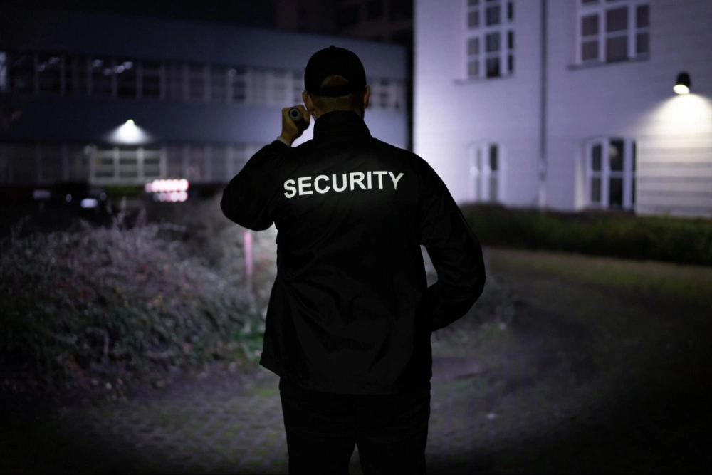 Security guard patrolling a property at night with flashlight, showcasing real-world applications of online security guard training from Guard Training.