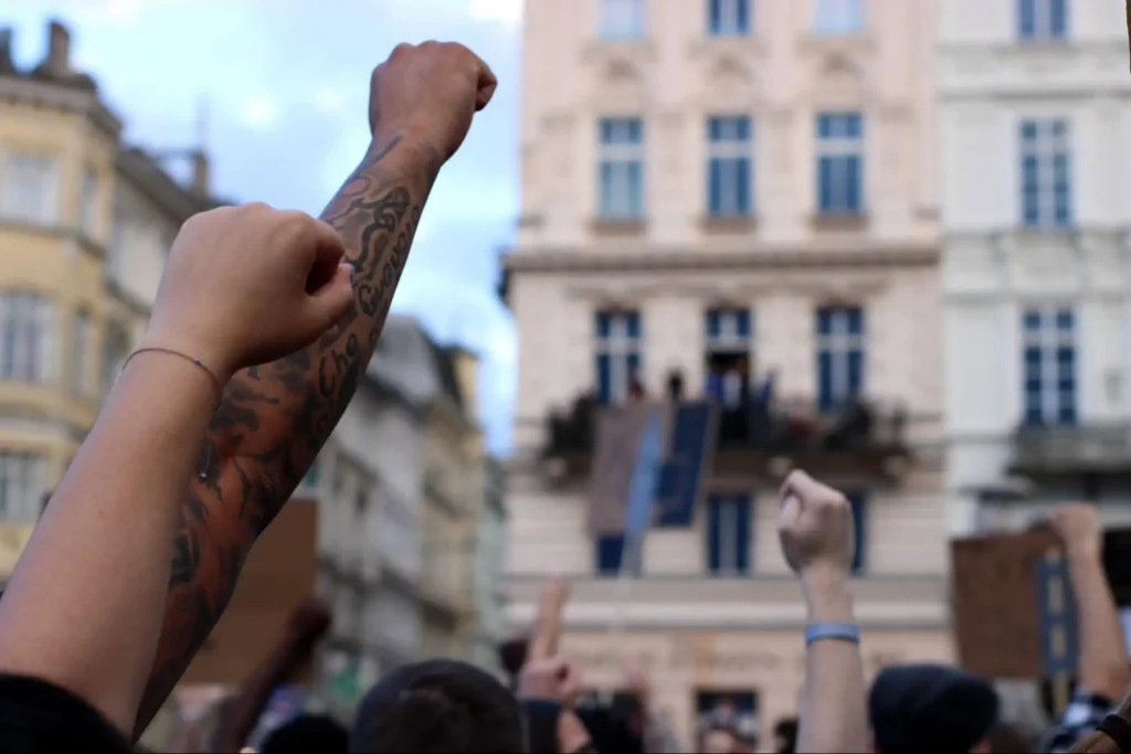 People raising fists during a public demonstration, illustrating crowd control scenarios in security guard training